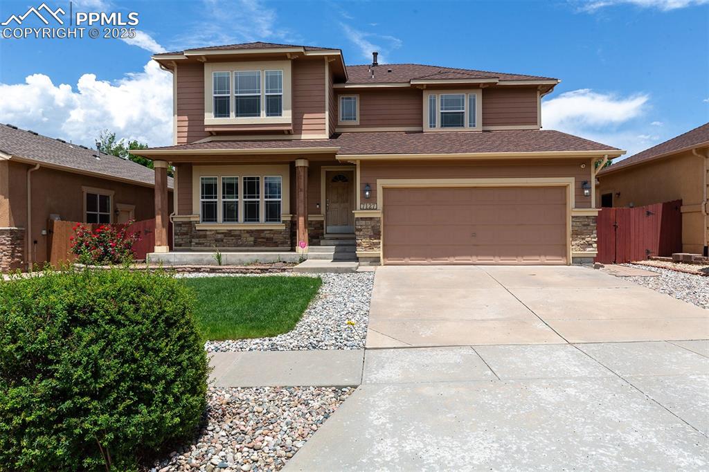 View of front of house featuring driveway, stone siding, an attached garage, and roof with shingles