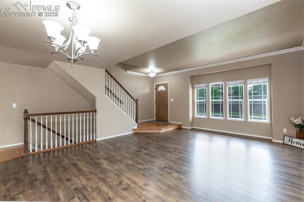 Entrance foyer featuring a chandelier, wood finished floors, and crown molding