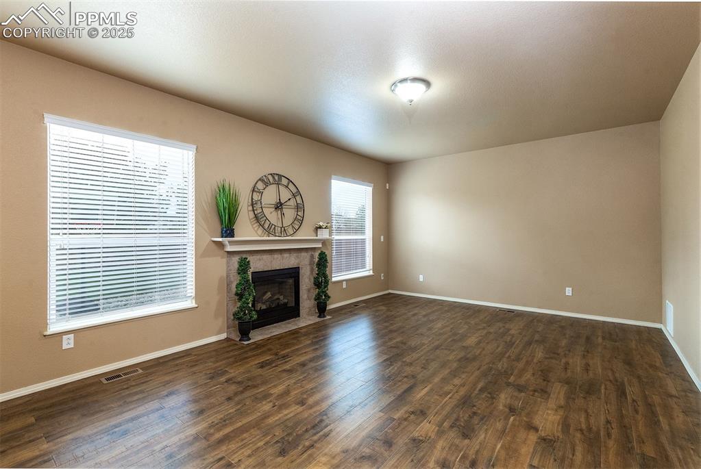 Unfurnished living room with dark wood-style floors and a tile fireplace