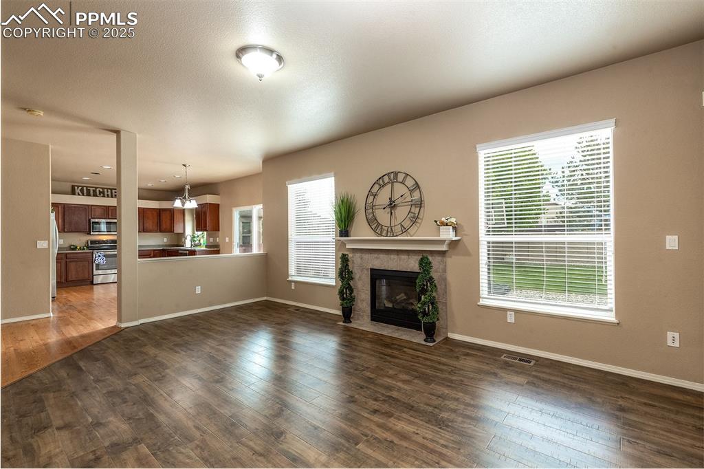 Unfurnished living room featuring a fireplace, dark wood-style flooring, and a chandelier