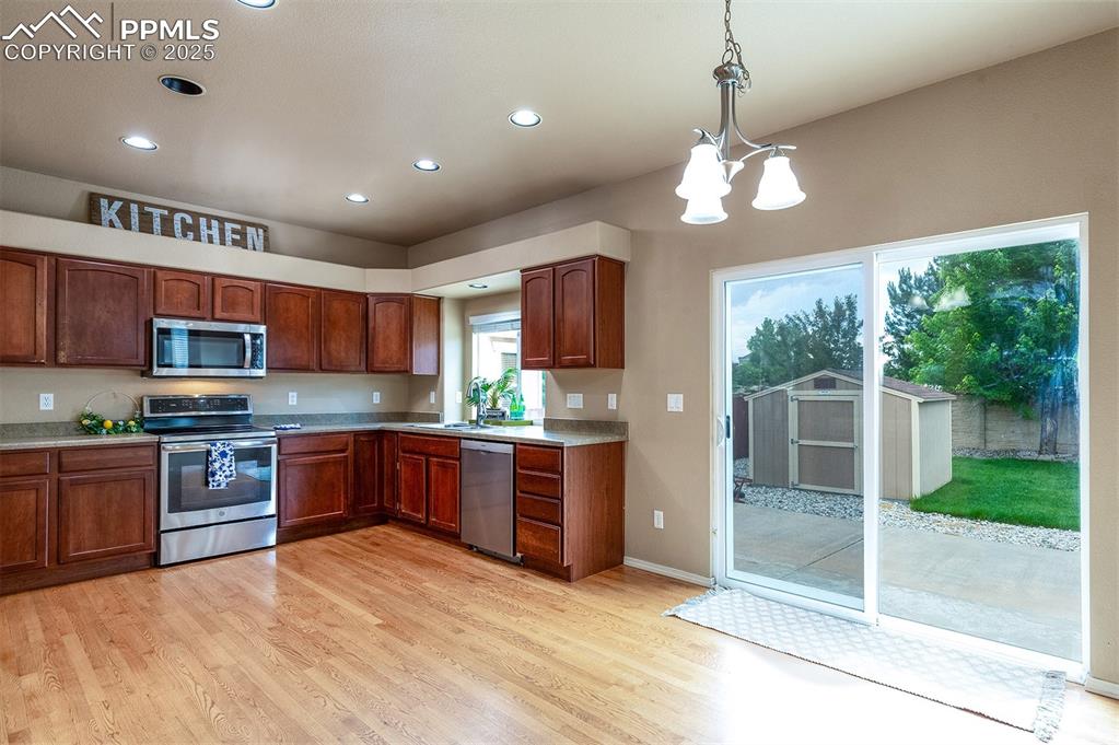 Kitchen featuring appliances with stainless steel finishes, recessed lighting, light wood-type flooring, hanging light fixtures, and light countertops