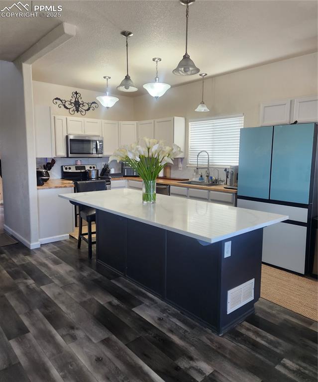 Kitchen with white cabinetry, fridge, pendant lighting, a kitchen breakfast bar, and dark cabinetry