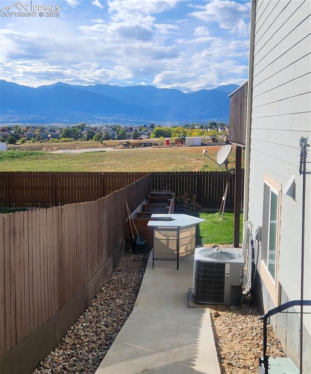 Fenced backyard featuring a mountain view and a patio area