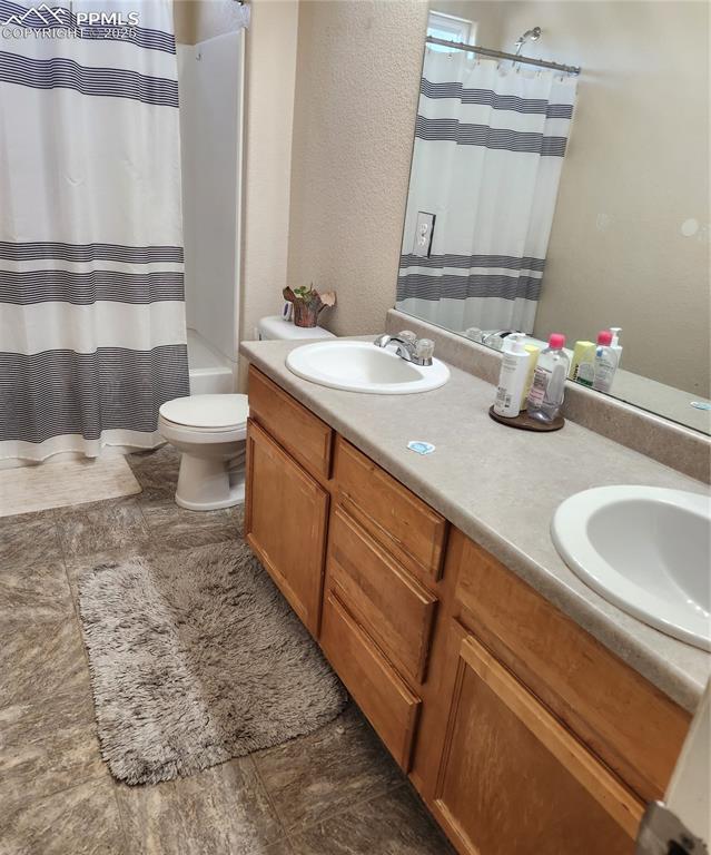 Upper common Bathroom featuring double vanity, shower / tub combo, and a textured wall