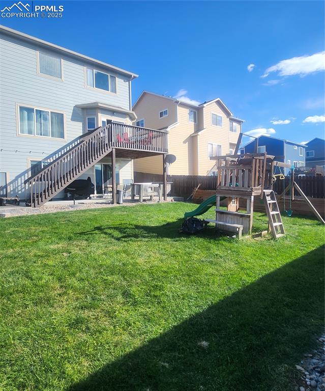 Back of property with a deck, stairs, a playground, a patio, and a residential view