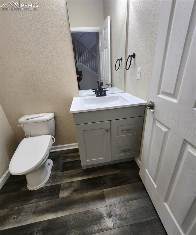Bathroom with a textured wall, vanity, and dark wood-style flooring