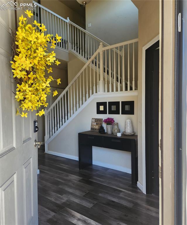 Entrance foyer featuring stairway, dark wood-style floors, and a towering ceiling