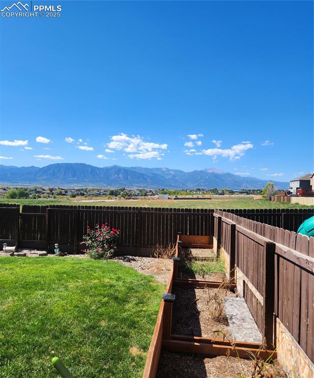 Fenced backyard with flower box featuring a mountain view and a vegetable garden box