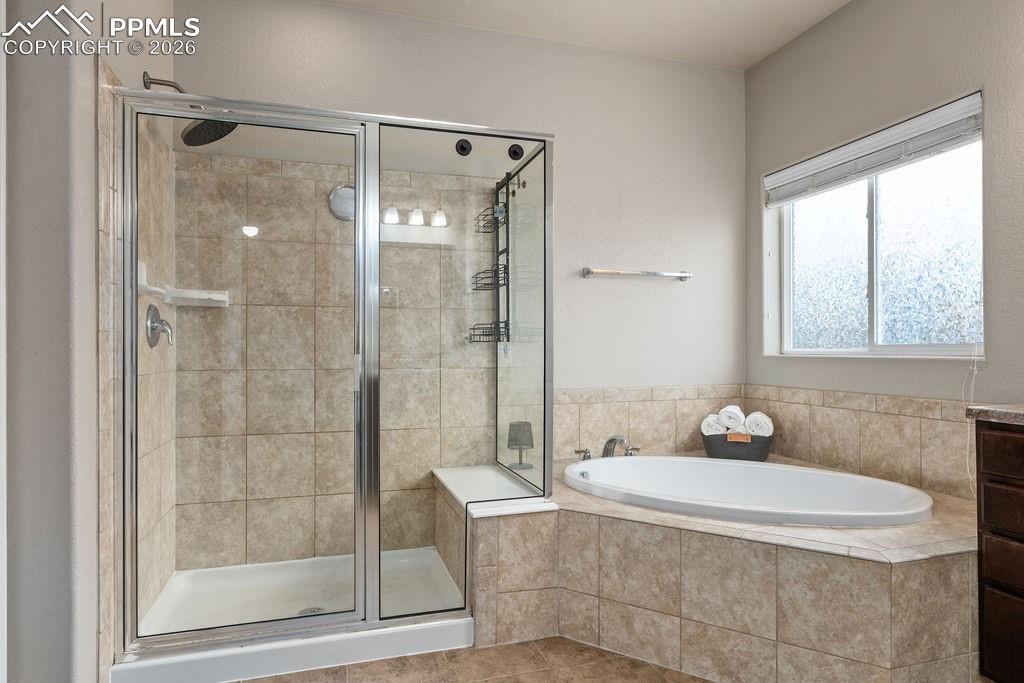 Bathroom featuring a stall shower, a garden tub, and vanity