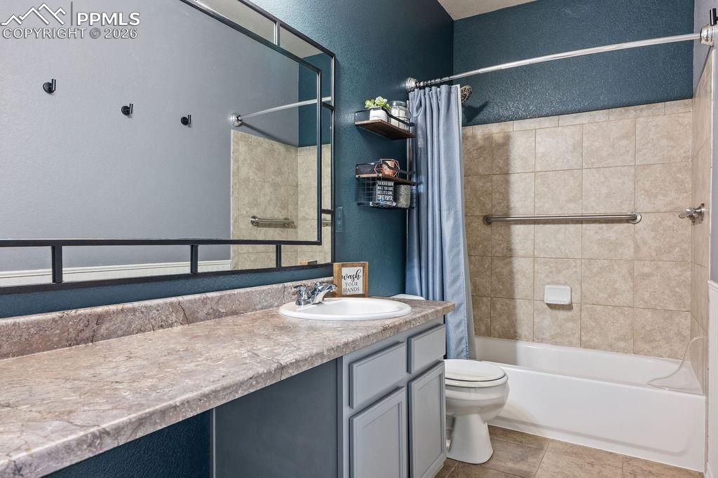 Upper floor bathroom with a textured wall, vanity, shower / bath combo, and light tile patterned floors