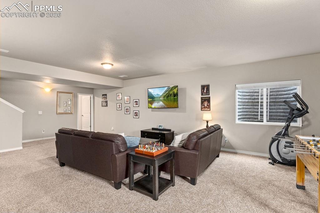 Basement recreation room featuring light carpet and a textured ceiling