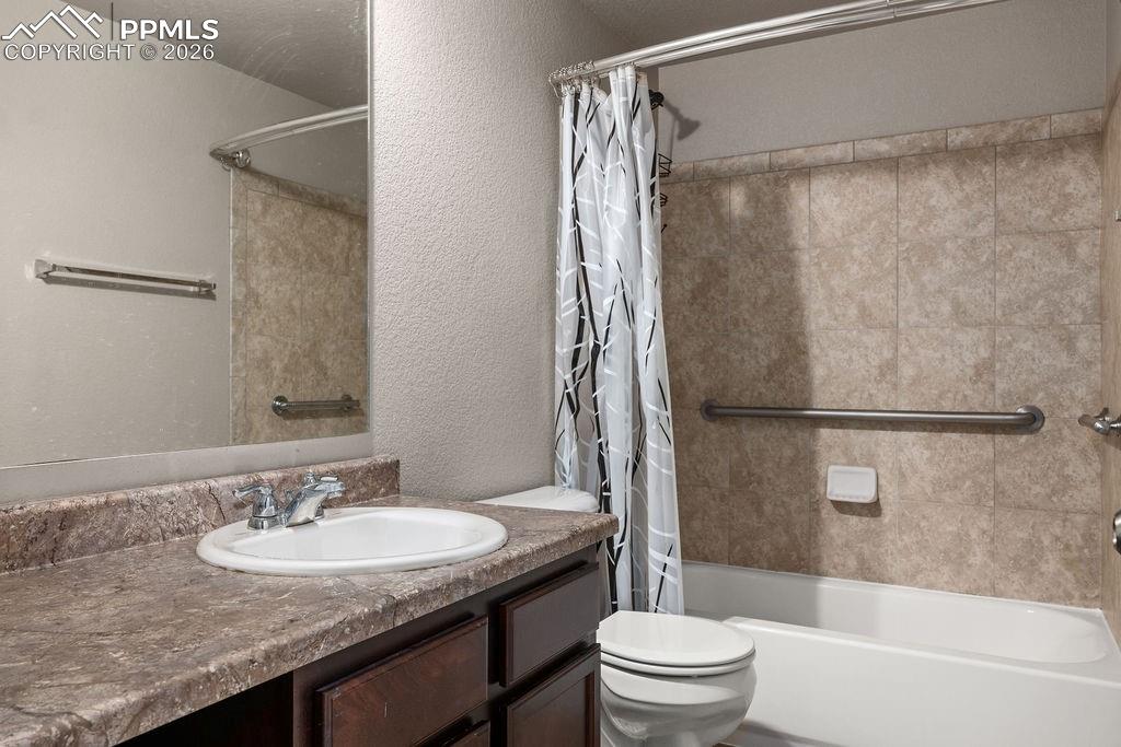 Basement full bath with vanity, a textured wall, and shower / tub combo with curtain