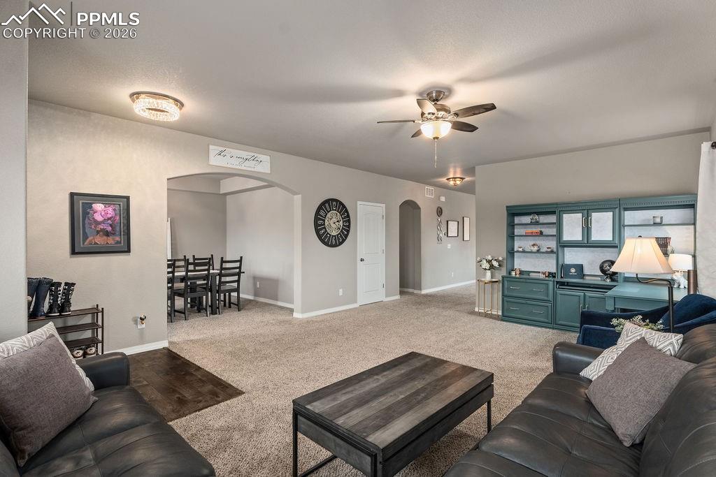 Sitting room featuring arched walkways, ceiling fan, and carpet floors