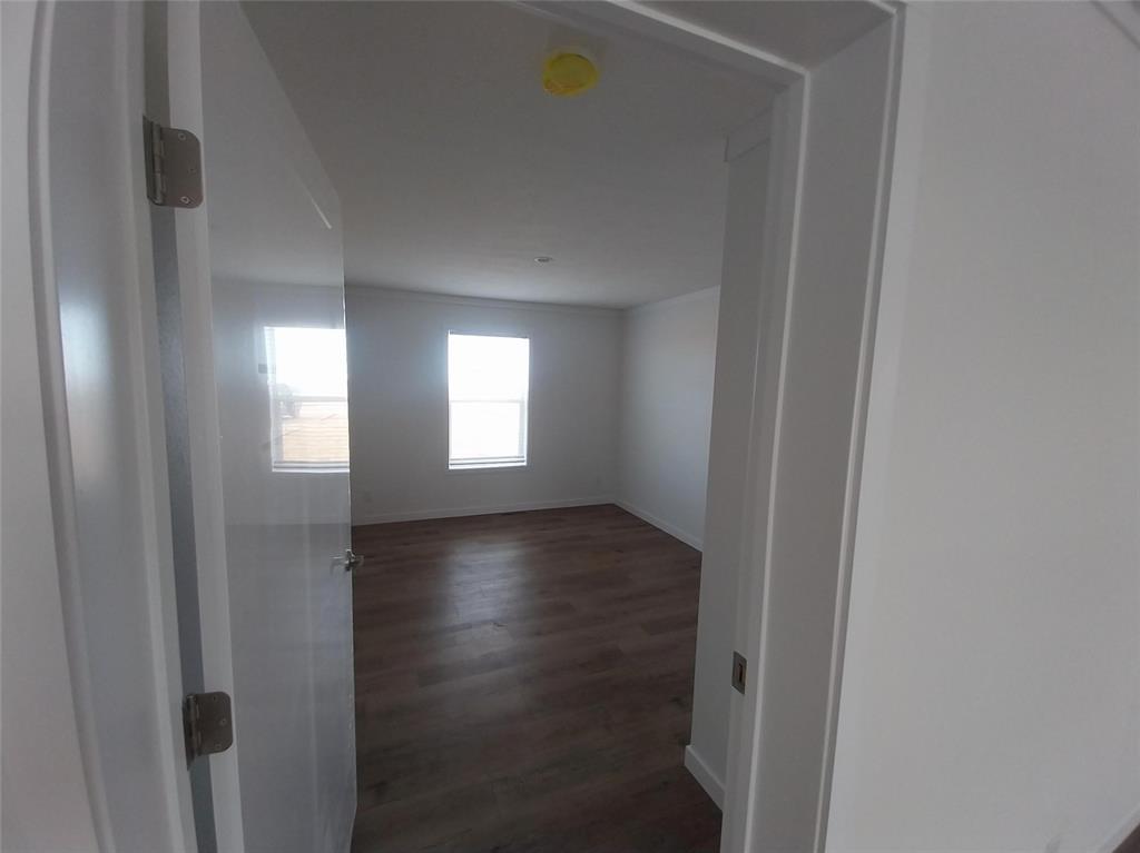 Spare room with dark wood-style flooring and a smoke detector