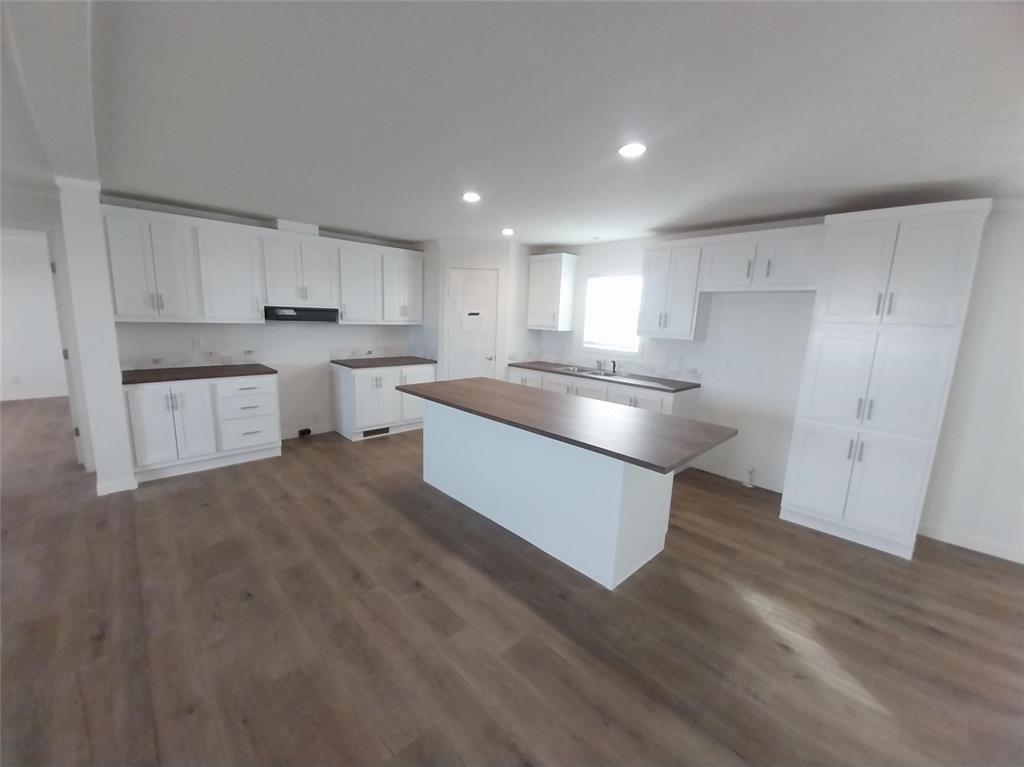 Kitchen with white cabinetry, dark wood-type flooring, a center island, dark countertops, and recessed lighting