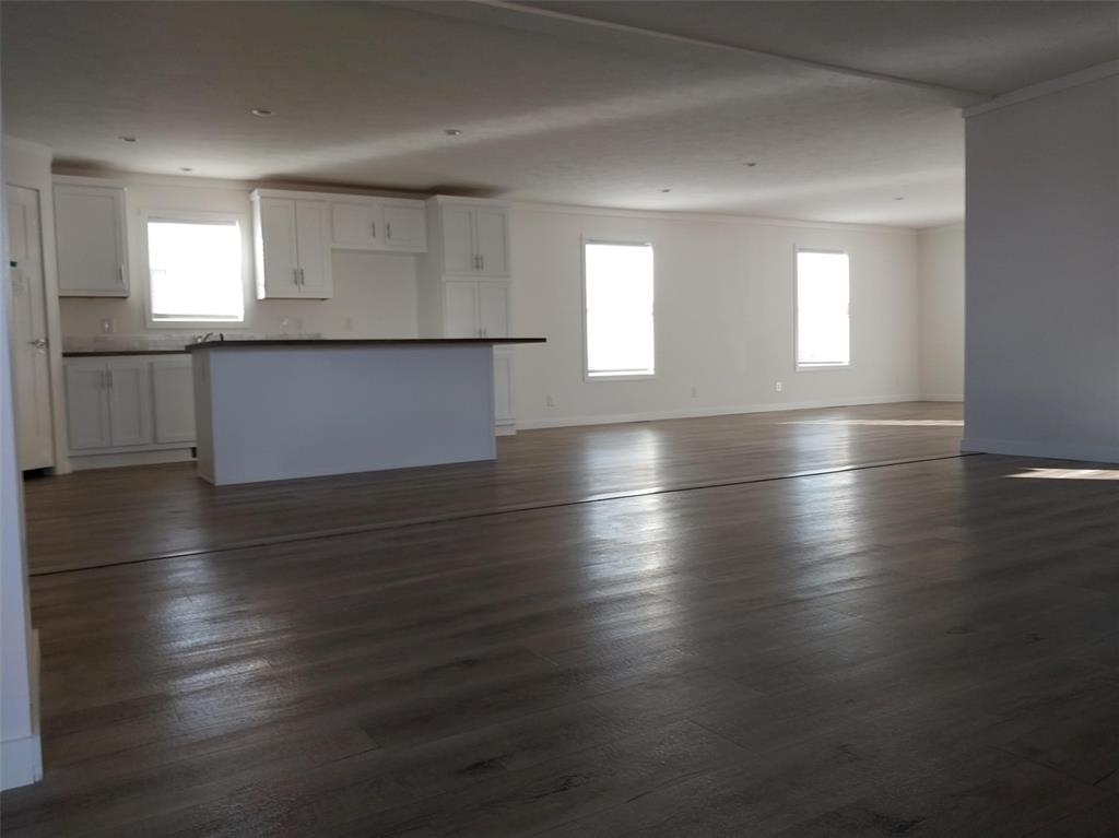 Unfurnished living room with dark wood finished floors and crown molding