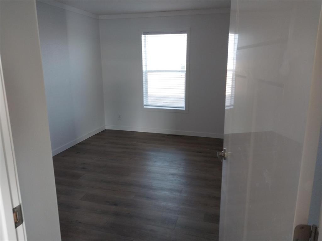 Empty room featuring ornamental molding and dark wood-style floors