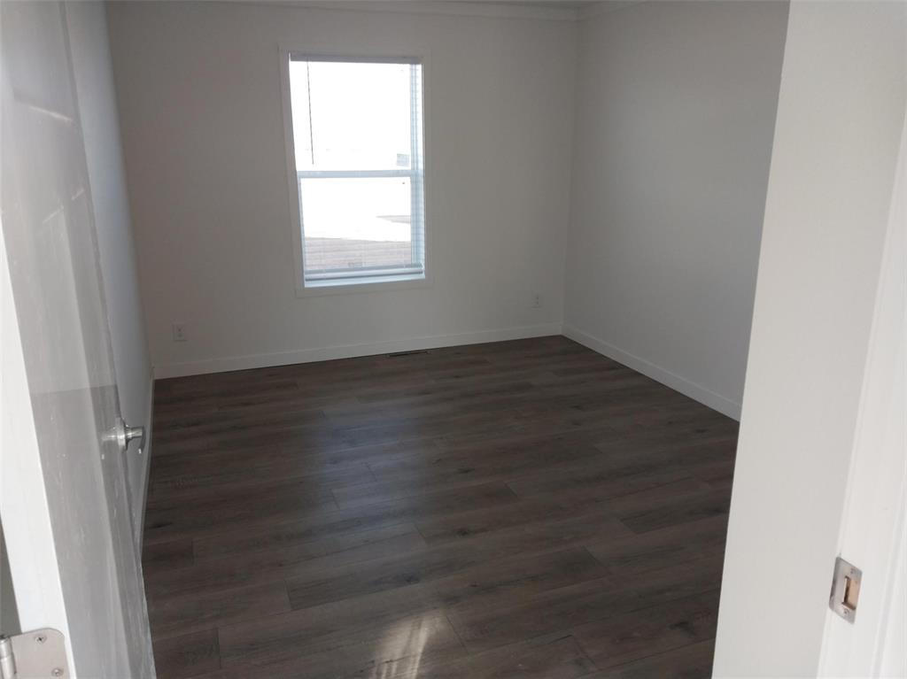 Unfurnished room with dark wood-type flooring and baseboards
