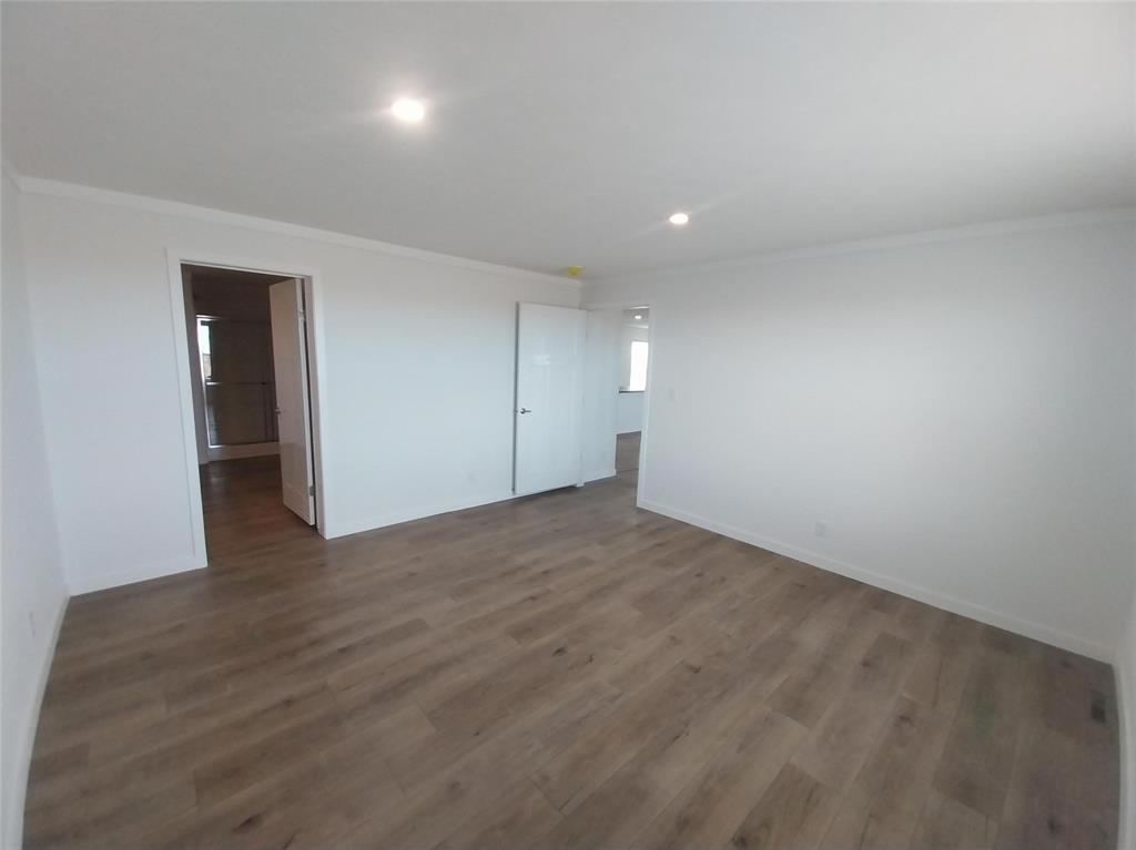 Empty room featuring ornamental molding, dark wood-type flooring, and recessed lighting