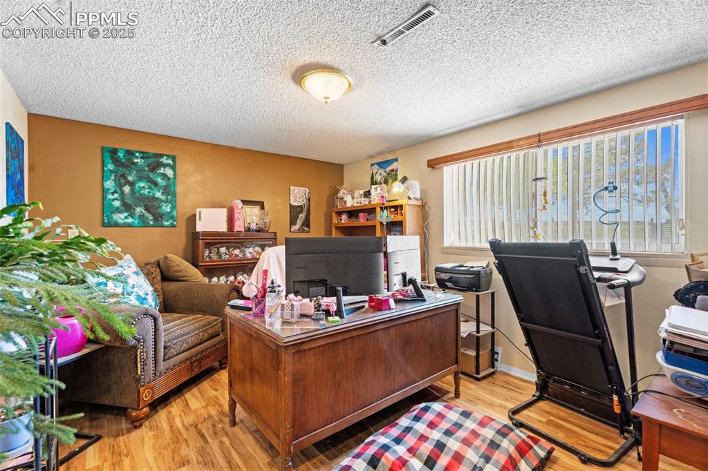 Home office with light wood-style floors and a textured ceiling. Great bonus room opportunity with lots of natural light. 