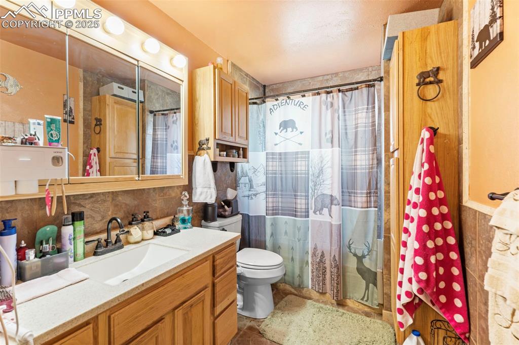 Full bathroom featuring vanity, a shower with shower curtain, tile walls, and decorative backsplash