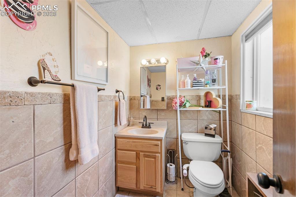 Bathroom featuring vanity, light tile patterned floors, tile walls, and wainscoting