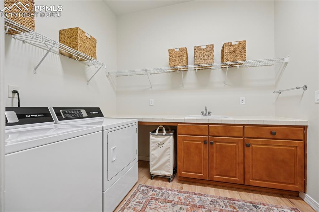 Laundry room featuring separate washer and dryer, light wood finished floors, and cabinet space