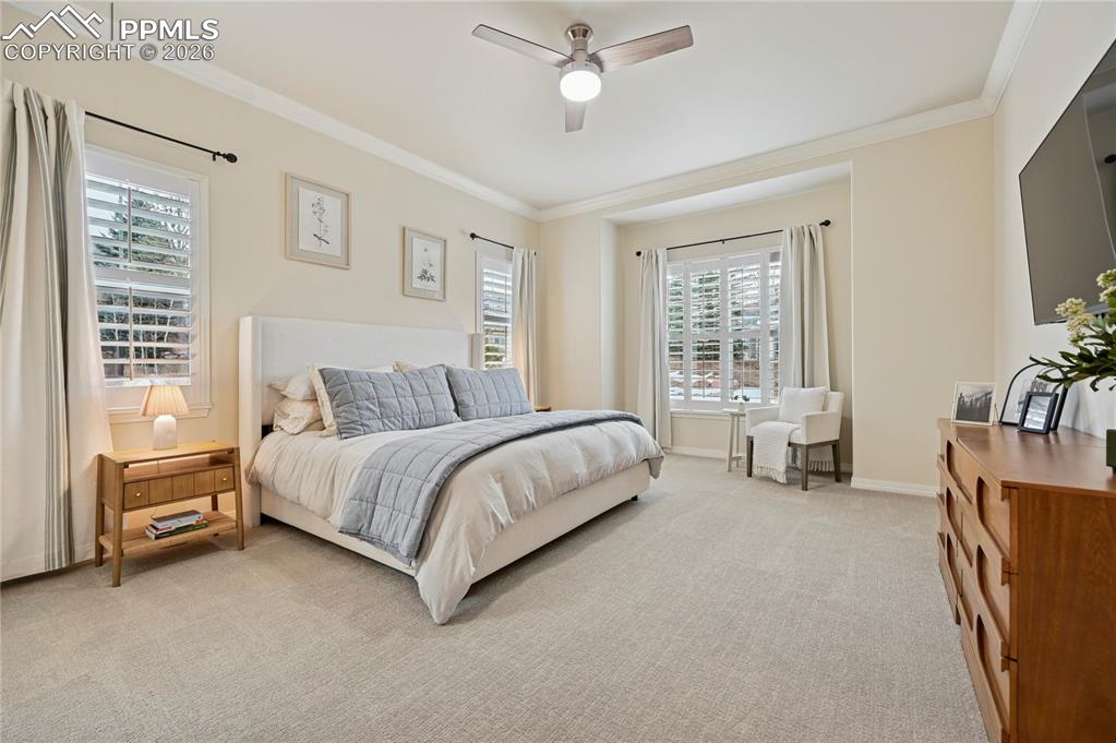 Bedroom featuring carpet floors, ornamental molding, and a ceiling fan