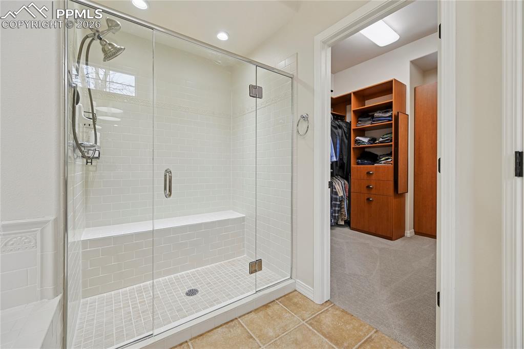 Full bathroom featuring a walk in closet, a shower stall, light tile patterned flooring, light carpet, and recessed lighting