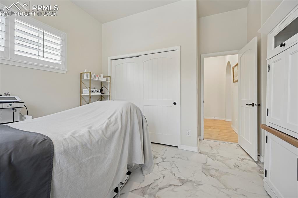 Bedroom with light marble finish flooring and a closet