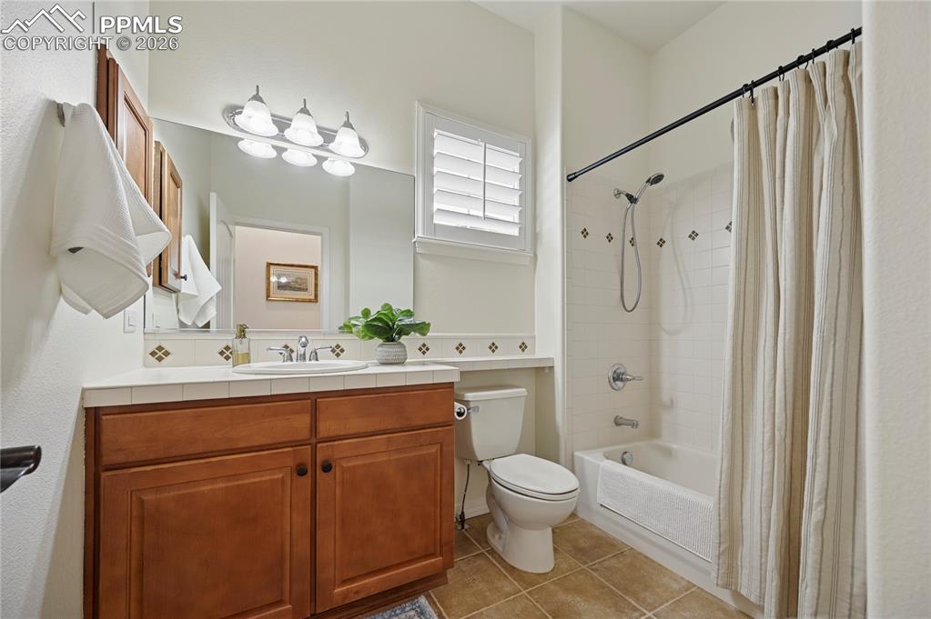 Bathroom featuring shower / bath combo with shower curtain, vanity, and light tile patterned floors