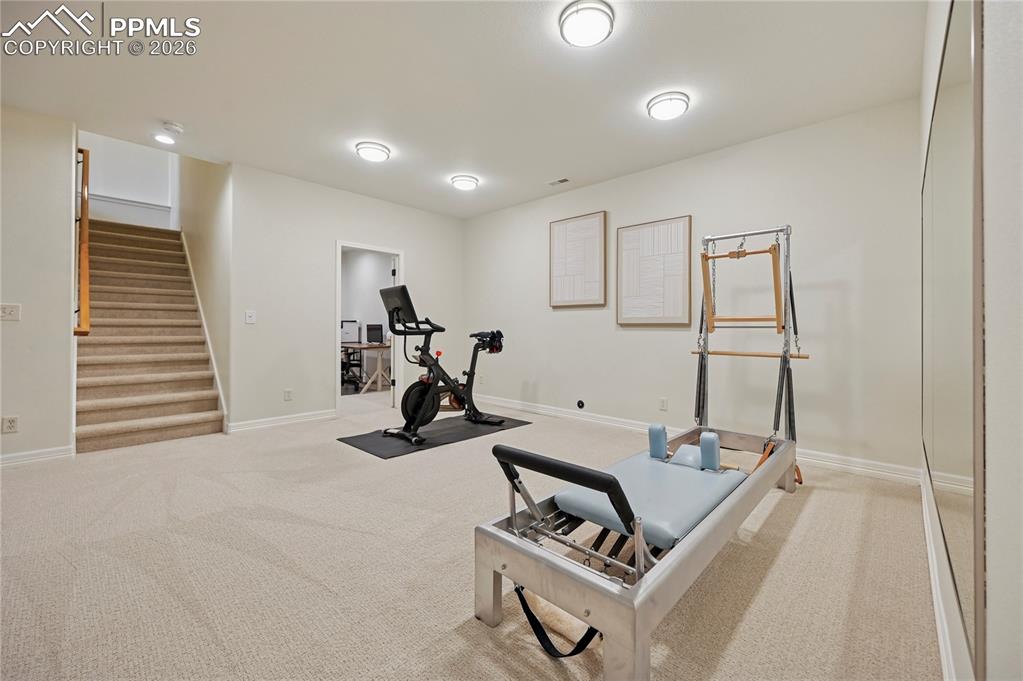 Exercise area featuring light colored carpet and baseboards