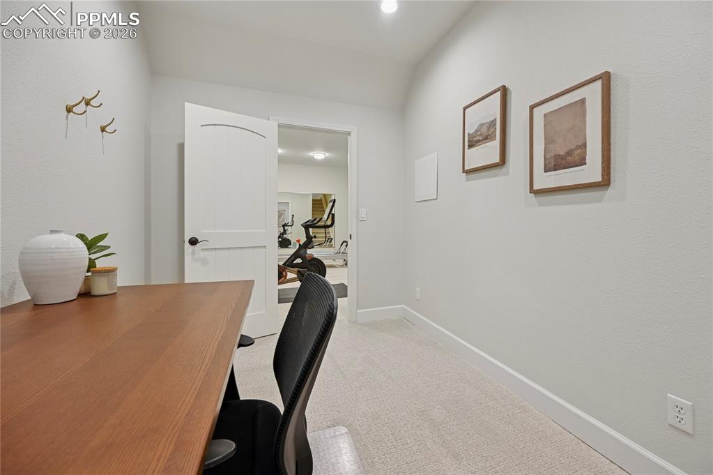 Home office featuring light carpet and vaulted ceiling