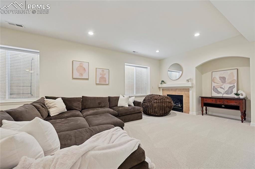Living room featuring a tile fireplace, carpet floors, and recessed lighting