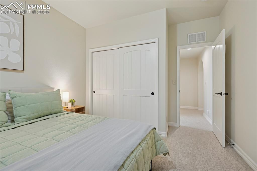 Bedroom with light colored carpet and a closet