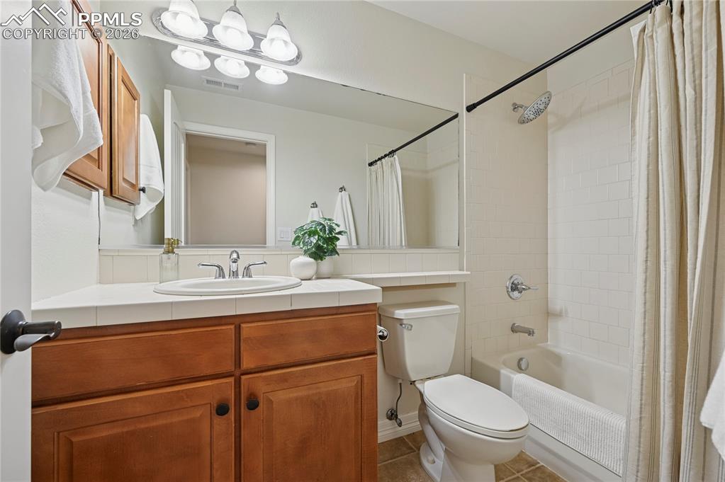 Bathroom featuring shower / bath combination with curtain, vanity, and tile patterned floors