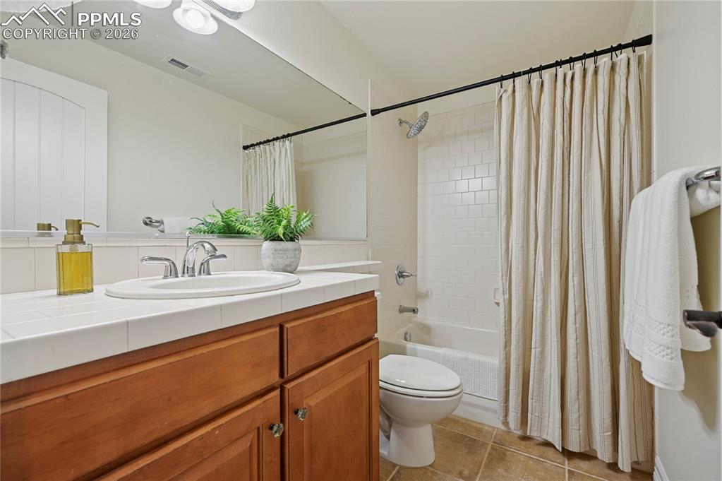 Full bath with shower / bath combo, vanity, and light tile patterned floors