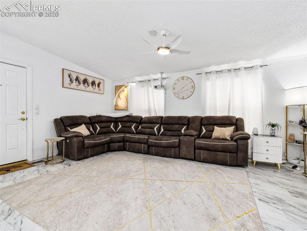 Living room with ceiling fan and a textured ceiling