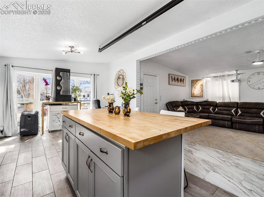 Kitchen featuring wooden counters, open floor plan, gray cabinets, a center island, and a textured ceiling
