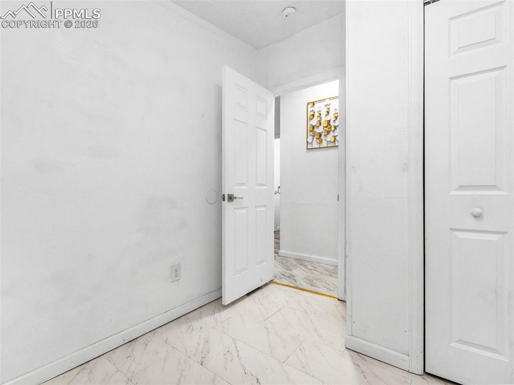 Unfurnished bedroom featuring baseboards and light marble finish floors