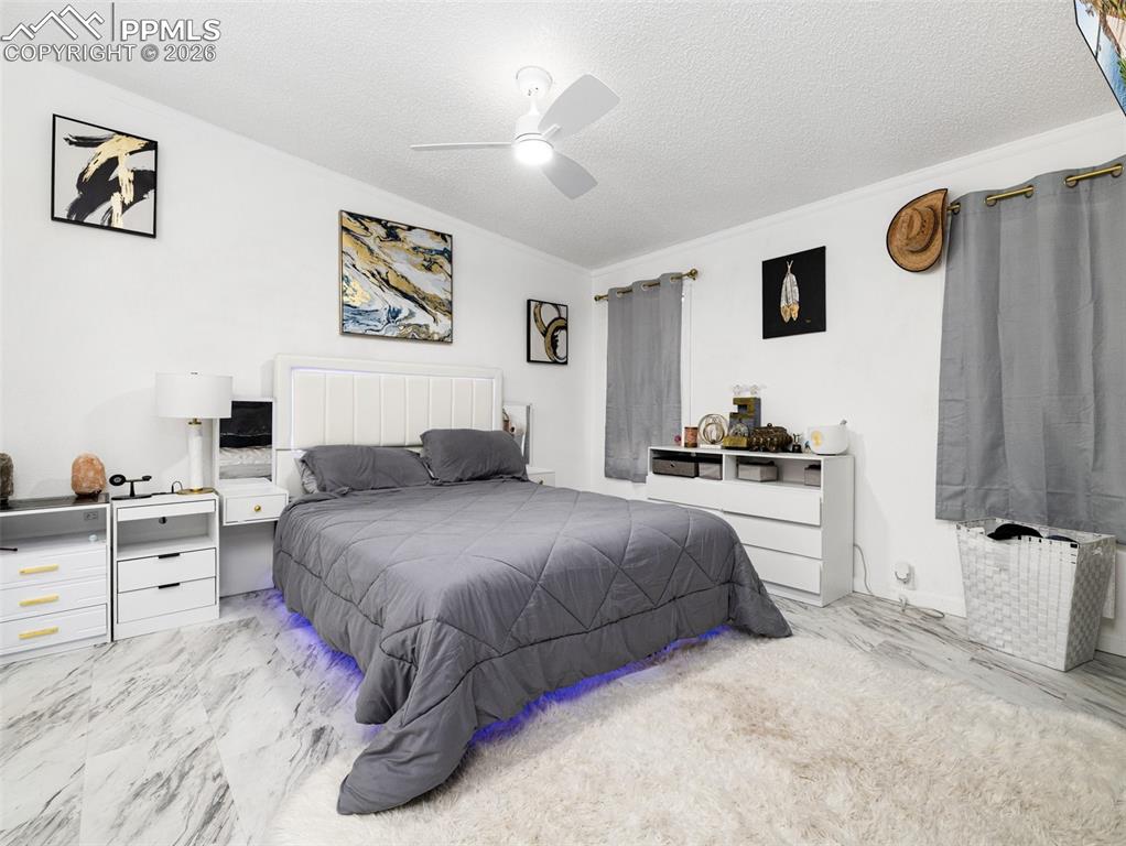 Bedroom with a textured ceiling, ceiling fan, and radiator heating unit