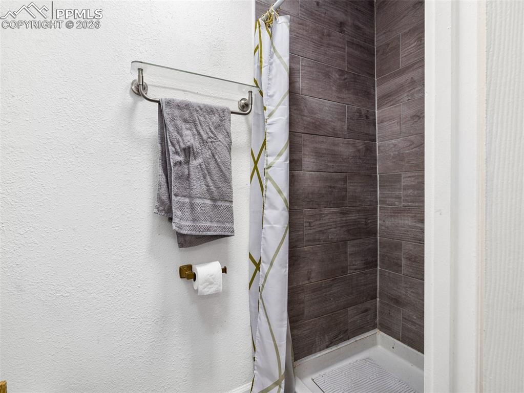 Full bath with a stall shower and a textured wall