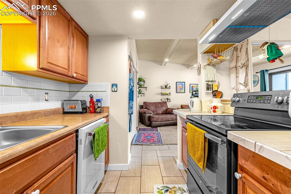 Kitchen featuring black electric range, wood finish cabinets, light countertops, white dishwasher, and open floor plan