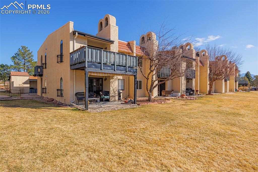 Back of property with a patio area, a lawn, a chimney, and stucco siding