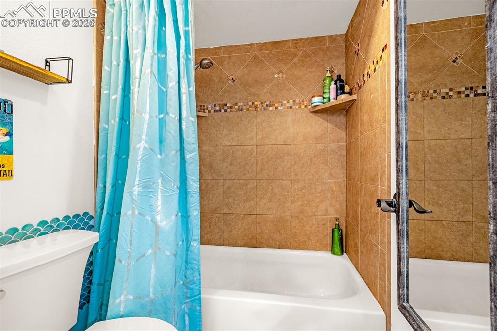 Bathroom featuring shower / bath combination with curtain and toilet
