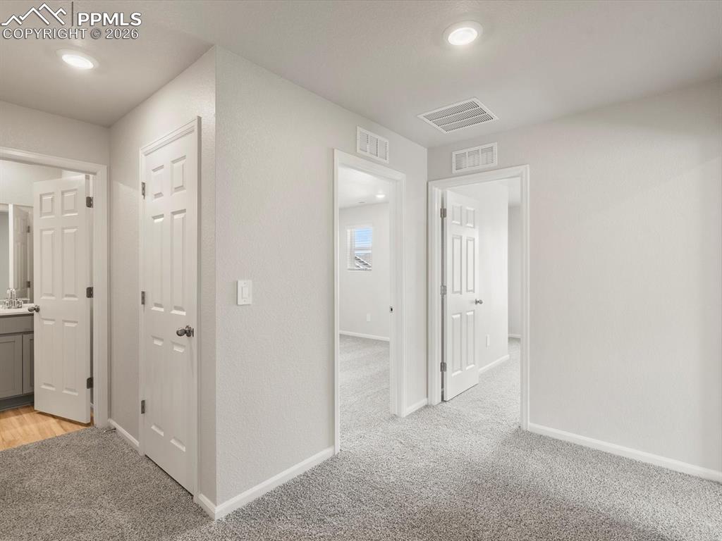 Hall featuring light colored carpet and baseboards