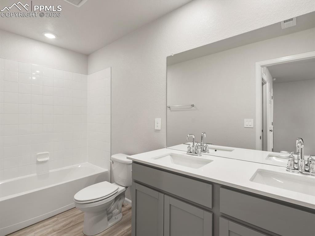 Full bathroom featuring bathing tub / shower combination, double vanity, and light wood finished floors