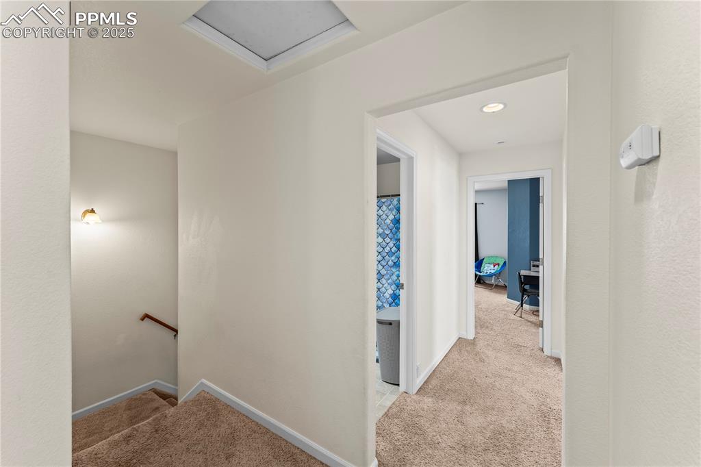 Hallway with light carpet and an upstairs landing