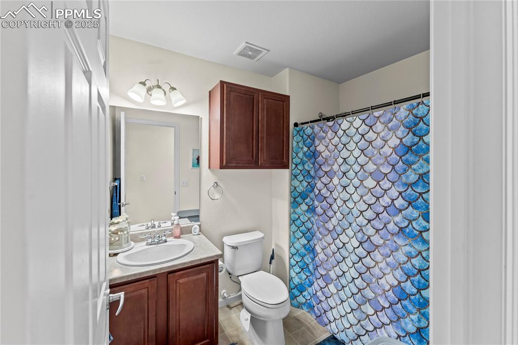 Full bath featuring vanity, a shower with curtain, and light tile patterned flooring