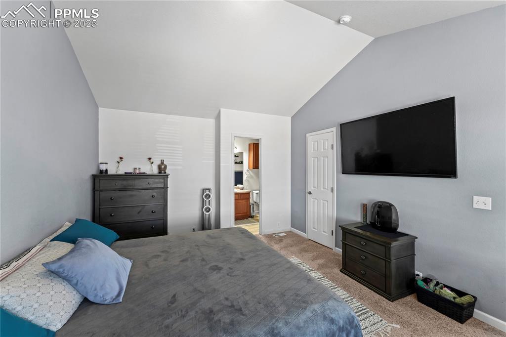 Bedroom featuring carpet floors, vaulted ceiling, and ensuite bathroom